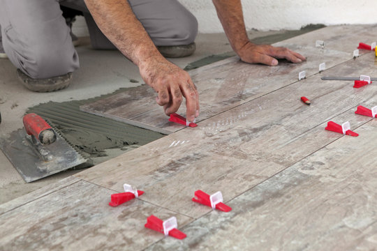 Ceramic Tiles. Tiler placing tille in position with lash tile leveling system