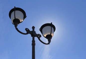 Fototapeta na wymiar Old lantern on a background of blue sky. Bottom view. onthe glass glare of the sun.