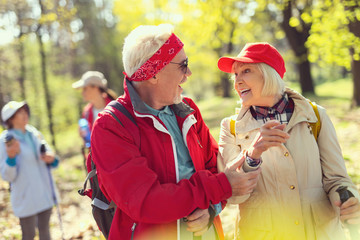 Nice talk. Inspired aged man smiling and talking with a woman while hiking