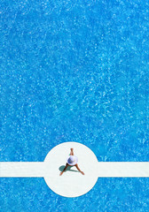 woman in a hat sitting on the edge of the pool