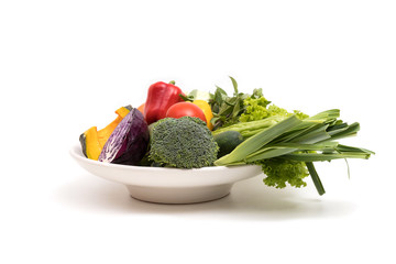 Assort fresh fruits and vegetables in dish isolated on white background