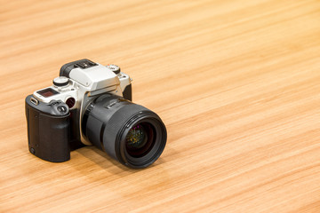 DSLR camera on wooden desk background.