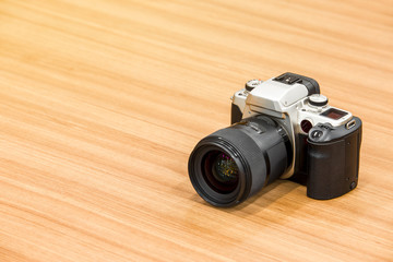 DSLR camera on wooden desk background.