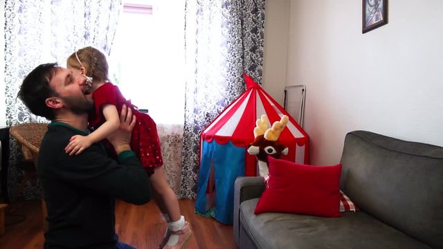 A cute little baby jumps into her father's hands in slow motion.