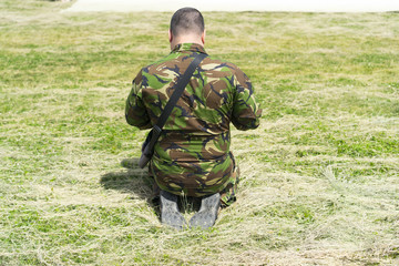 Soldier on his knees, praying and surrendering, prisoner asks for mercy