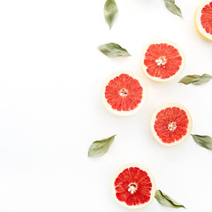 Sliced grapefruits and green leaves on white background.