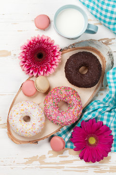 Milk, donuts and flowers on wooden table