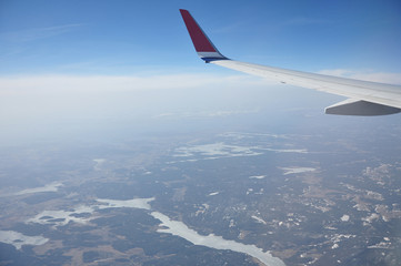 Obraz premium Norwegian landscape under the wings of an airplane flying over the clouds.