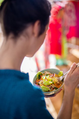 A young woman eating a salad in a bowl