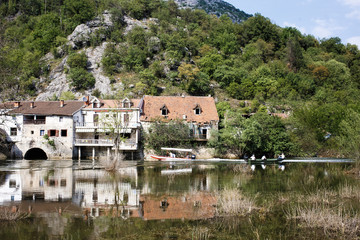 Fototapeta premium Old stone house with orange roof jn the river, shutters on the windows. Montenegro