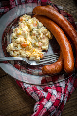 Thin sausages with vegetable salad on plate.