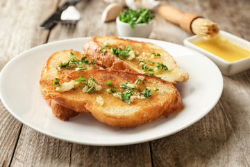 Plate with delicious homemade garlic bread on table