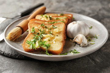 Plate with delicious homemade garlic bread on table