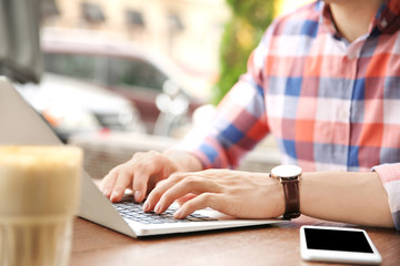 Fototapeta premium Young man working with laptop at desk, closeup