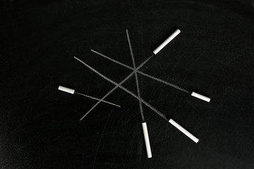 Chalk sticks on blackboard, closeup. School equipment