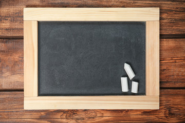 Empty clean blackboard with chalk on wooden background