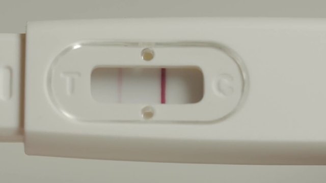 Positive pregnancy test in hands. Extremely close up shot.