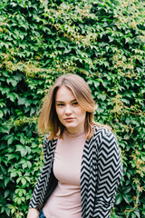 Portrait of a stylish woman against a green foliage background.