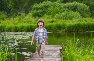 barefoot boy is on a wooden bridge on the river