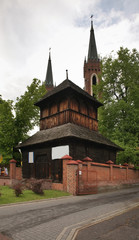 Fototapeta na wymiar Wooden belfry and Parish church of St. John Baptist in Parczew. Poland