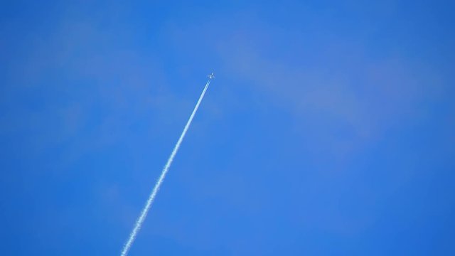 Jet Airplane Flying Smoothly Overhead in a Blue Sky with White Contrails on a Sunny Day