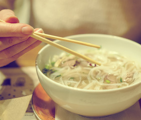Woman eating Vietnamese classic noodle soup. © M-Production