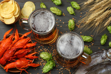 Glass beer with crawfish, dried fish and hop cones on dark wooden background. Beer brewery concept....