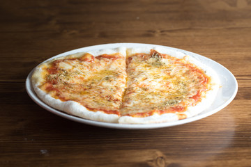 Pizza with cheese and garlic on a white plate and wooden background