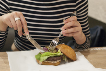 Burger in beautiful female hands. Close-up. Background of no sharpness
