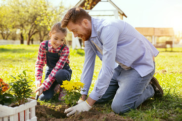 Naklejka na ściany i meble Funny activity. Joyful positive father and daughter having fun while planting flowers together