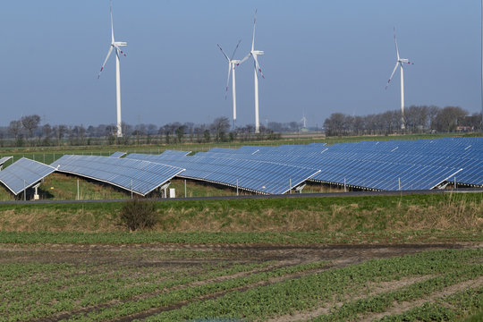 Ein Solarfeld mit Windr&auml;dern im Hintergrund