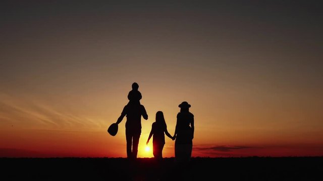 Slow Motion Silhouette at sunset happy family walking through a meadow