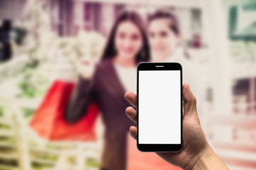 Hold mobile on the background people are shopping in the mall.