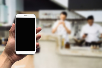 Hold mobile on the chef's cooking background.