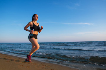 Fototapeta na wymiar Healthy young fitness woman runner running on sunrise seaside trail