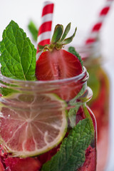 Close up view lime and strawberry detox in glass mason jars macro. Fitness summer drink. Selective focus. 