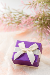 Small purple jewelry gift box with bow on lace background