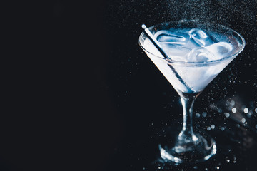 Large cocktail in martini glass with droplets of spray is prepared by barman.