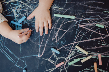 Close-up of child hand draws on chalkboard, top view