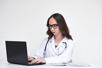 Portrait of beautiful brunette doctor girl on white background with laptop.