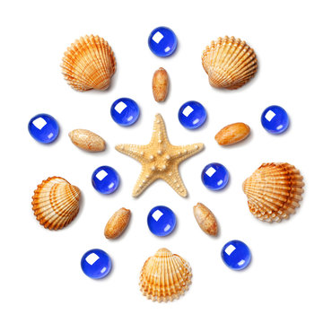 Pattern in the form of a circle made of shells, starfish and green, blue and yellow glass beads isolated on white background