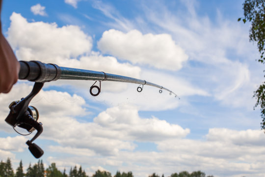 fishing rod on a blue sky background in a man's hand