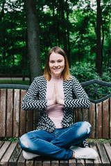 Portrait of a stylish woman on a wooden bench in the park.