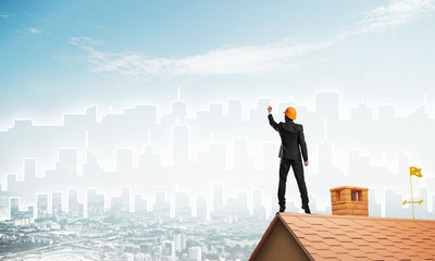 Man architect draw silhouette of modern city on blue sky. Mixed media