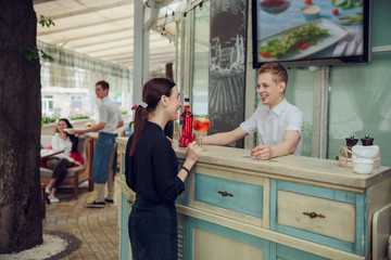 Obraz premium view of man standing at bar counter and making cocktail for woman staying near.