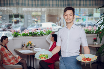 Close up view of waiter serving dishes at restaurant