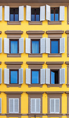 Windows with shutters on bright yellow facade