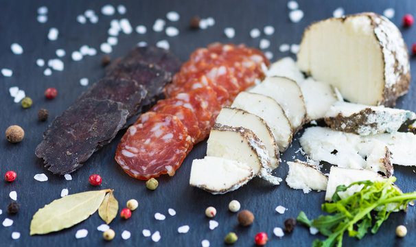 Sliced sausage with cheese and spised on a slate desck background