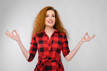 Young red-haired girl in a red checkered shirt. Young girl meditates