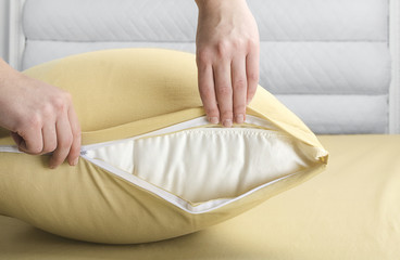 Woman making bed and changing pillow in guest room